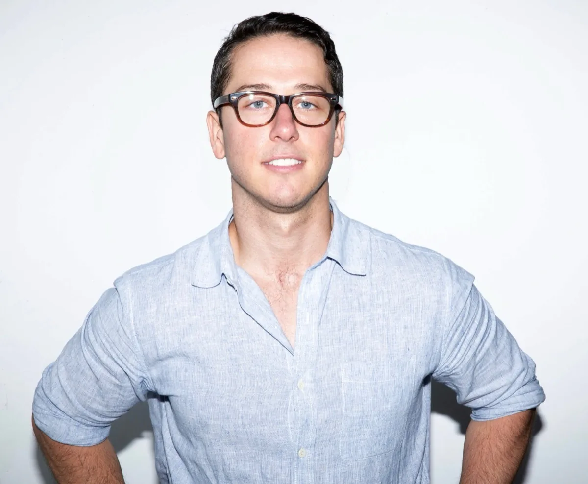 Andrew Rothaus, founder of Longsleeve, in a blue linen shirt against a white wall.